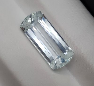 un diamant taille émeraude posé sur un tissu blanc