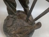 bronze statue of a man with a pitchfork and a dog