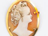 Une broche en or représente le profil d'une femme.
