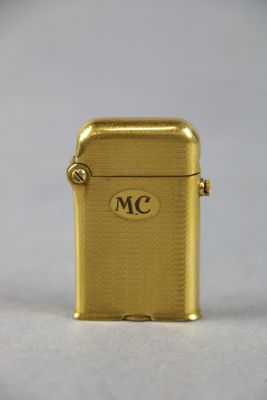 un gros plan d'un briquet doré posé sur une surface blanche