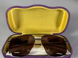 étui violet et jaune contenant des lunettes de soleil, posé sur une surface blanche