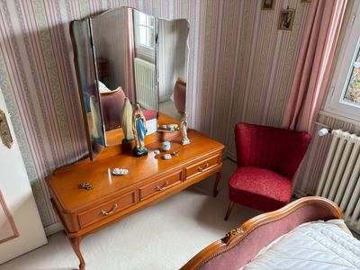 a bedroom with a bed, dresser, mirror, and chair in it
