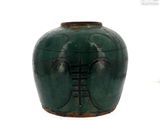 un vase vert orné d'une échelle, posé sur une surface blanche