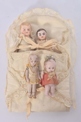 three dolls sitting in a bag on a white surface