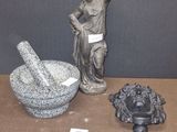 une boîte sur laquelle est posée une statue représentant un homme tenant un mortier et un bol