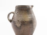 a brown vase that is sitting on a white surface