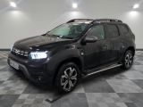 La Dacia noire est garée dans une grande pièce au sol carrelé en damier.