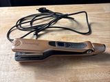 le fer à lisser est posé sur une table en bois, à côté d'une paire de lunettes