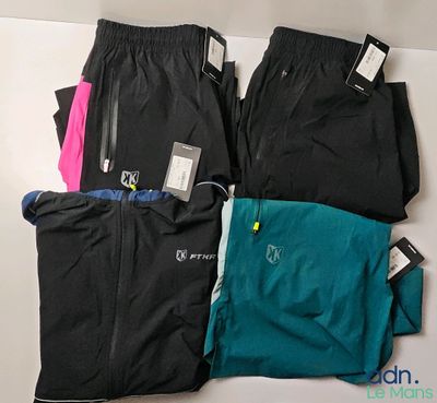 Trois paires de pantalons de course et une paire de chaussures de course sont disposées sur une table.