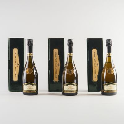 trois bouteilles de champagne sont alignées sur une surface blanche