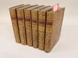 six vieux livres empilés les uns sur les autres sur une surface blanche