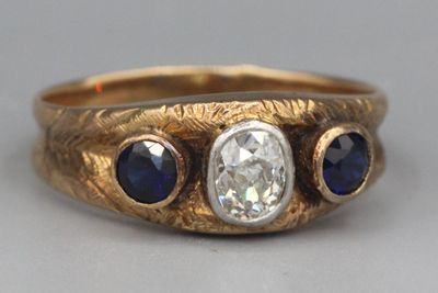 Bague en or ornée d’un diamant épaulé de deux saphirs.