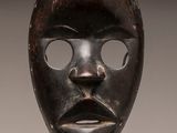 a close up of a wooden mask on a stand on a table