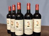 six bottles of red wine are lined up on a wooden table