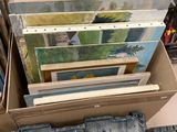 beaucoup de tableaux dans une boîte posée par terre