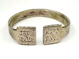 a close up of a silver bracelet with two squares on it