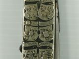 a small silver object with a design on it