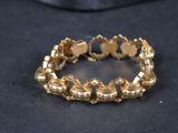 gros plan d'un bracelet en or sur une surface noire