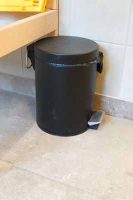 une poubelle noire posée à côté d'une poubelle jaune