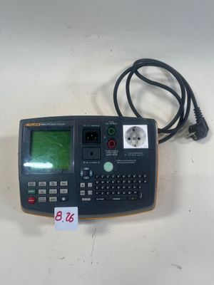 une image représentant une calculatrice posée sur une table, à côté d'un cordon d'alimentation