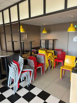 des chaises et des tables aux couleurs vives dans un restaurant au sol à carreaux