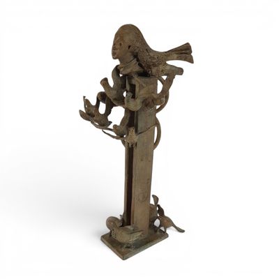 an old bronze statue of a woman holding a bird on a branch