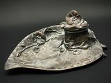 une assiette en argent ornée d'une fleur sur un fond noir