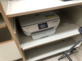 a printer sitting on a shelf in the corner of a room