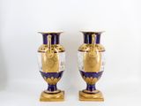 pair of blue and gold vases sitting on top of a white surface