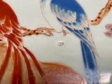 two birds sitting on a tree branch painted on a plate