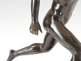 bronze statue of a man running on a marble base