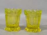 pair of yellow glass vases sitting on top of a white surface