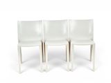 three white chairs sitting next to each other on a white surface
