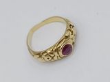 a close up of a gold ring with a red stone