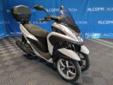 une photo d'un scooter blanc et noir garé devant un fond bleu