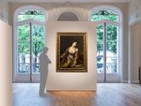 a man standing in a room with a painting on the wall
