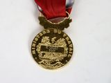 a gold medal with a red ribbon on a white table