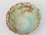 a green bowl with a red rim on a white surface