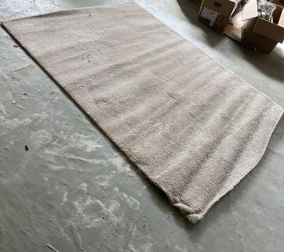 un tapis posé à même le sol dans un entrepôt, avec des cartons à perte de vue en arrière-plan