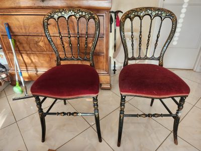 une paire de chaises aux assises recouvertes de velours rouge, placées devant une commode
