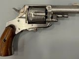 un vieux revolver avec une poignée en bois sur une surface blanche