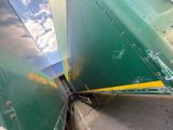 a green and yellow train that is going down the tracks
