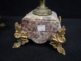 a gold and red vase on a stand with a label on it