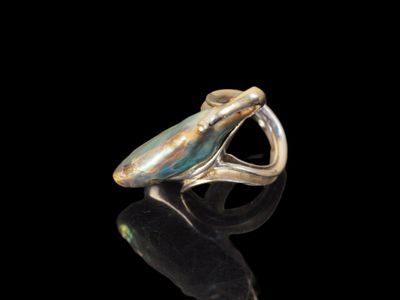 un gros plan d'une bague posée sur une surface noire, avec un fond noir