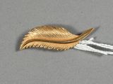 une feuille d'or suspendue à un fil blanc sur une surface grise