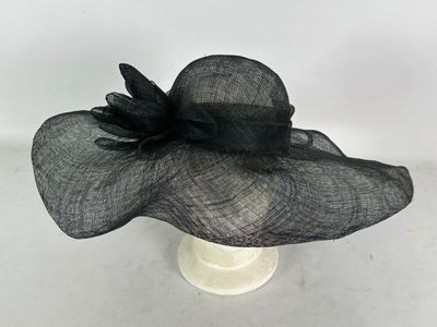 un gros plan sur un chapeau noir orné d'une fleur