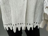 a close up of a woman ' s white sweater with holes on it