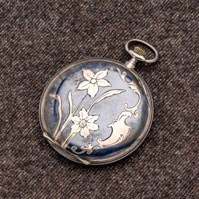 un gros plan d'une montre de poche ornée d'un motif floral