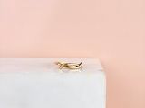 un gros plan d'une bague en or posée sur un bloc de marbre
