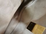 beige leather handbag with a gold metal plate on top of it